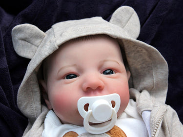 A baby doll rests on a soft blanket beside a cuddly teddy bear, creating a cozy and playful scene.